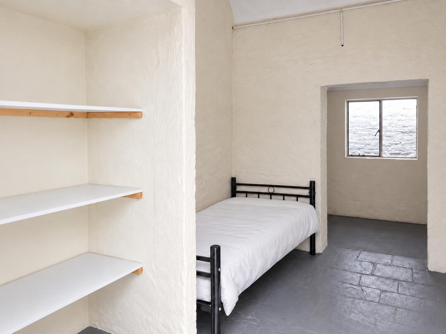 A single bed beside built-in shelves